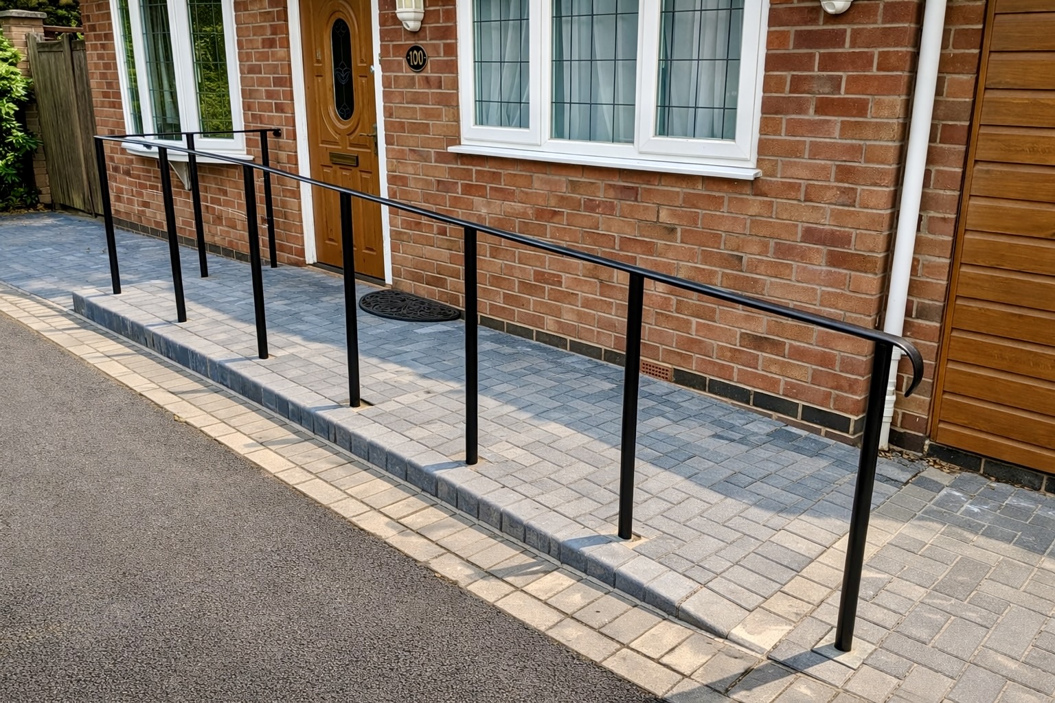 Block paved wheelchair ramp with handrails providing level access to a residential entrance in Leamington Spa.